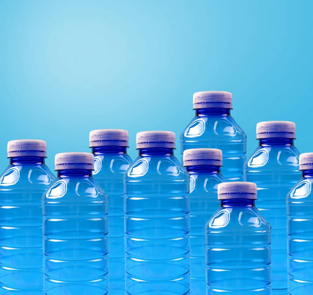 Group of blue plastic bottles symbolizing recycling and zero waste on a gradient background.