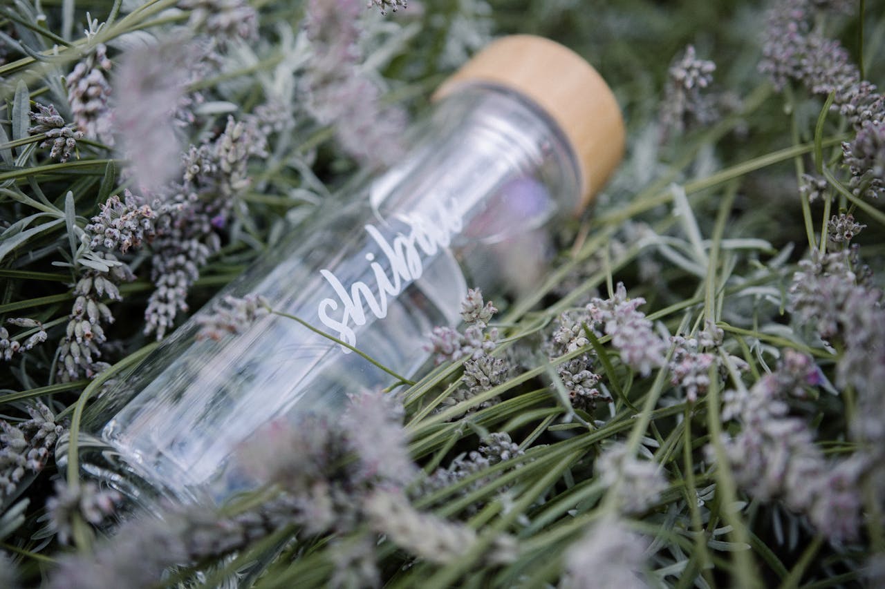 Glass water bottle with bamboo lid in a lush lavender field, emphasizing sustainability.